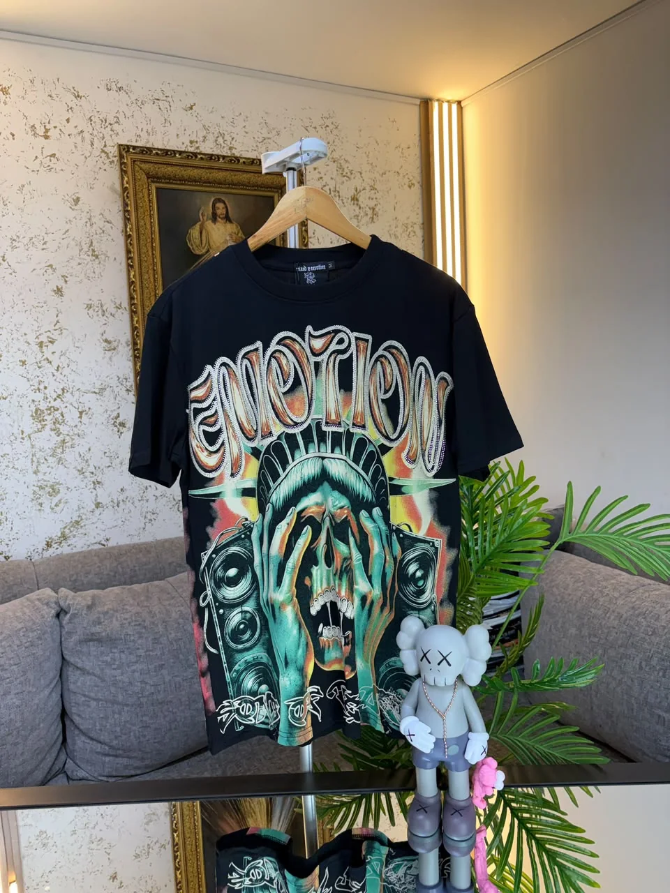 La camiseta Emotion colgada en la tienda, con la pared dorada de fondo